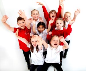 A group of children from a Little Voices class, not a drama club. They're wearing a mixture of red, and white, polo shirts and hoodies.